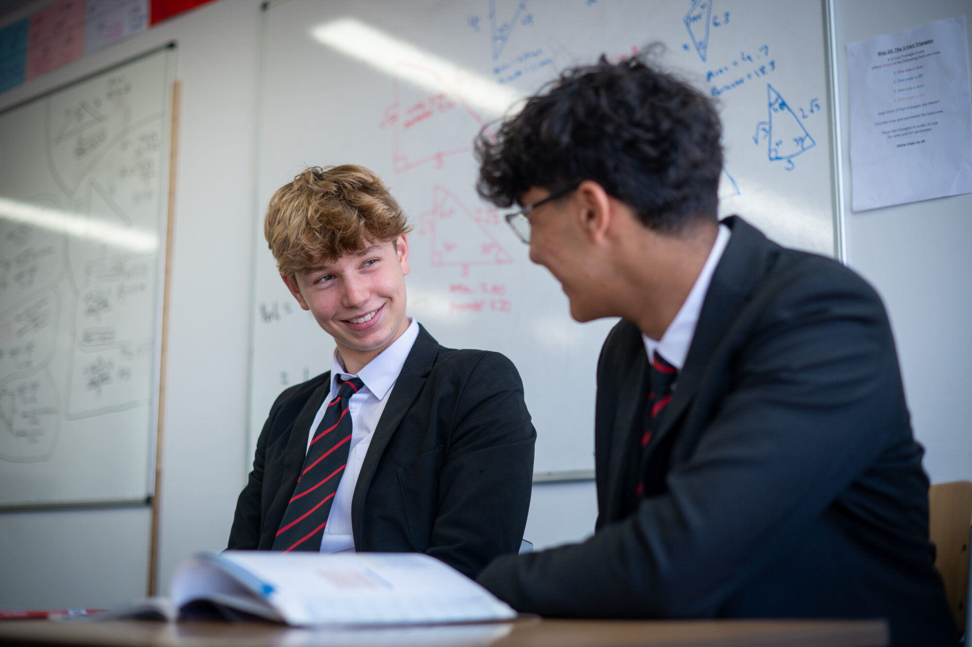 Two male school pupils discussing a book.